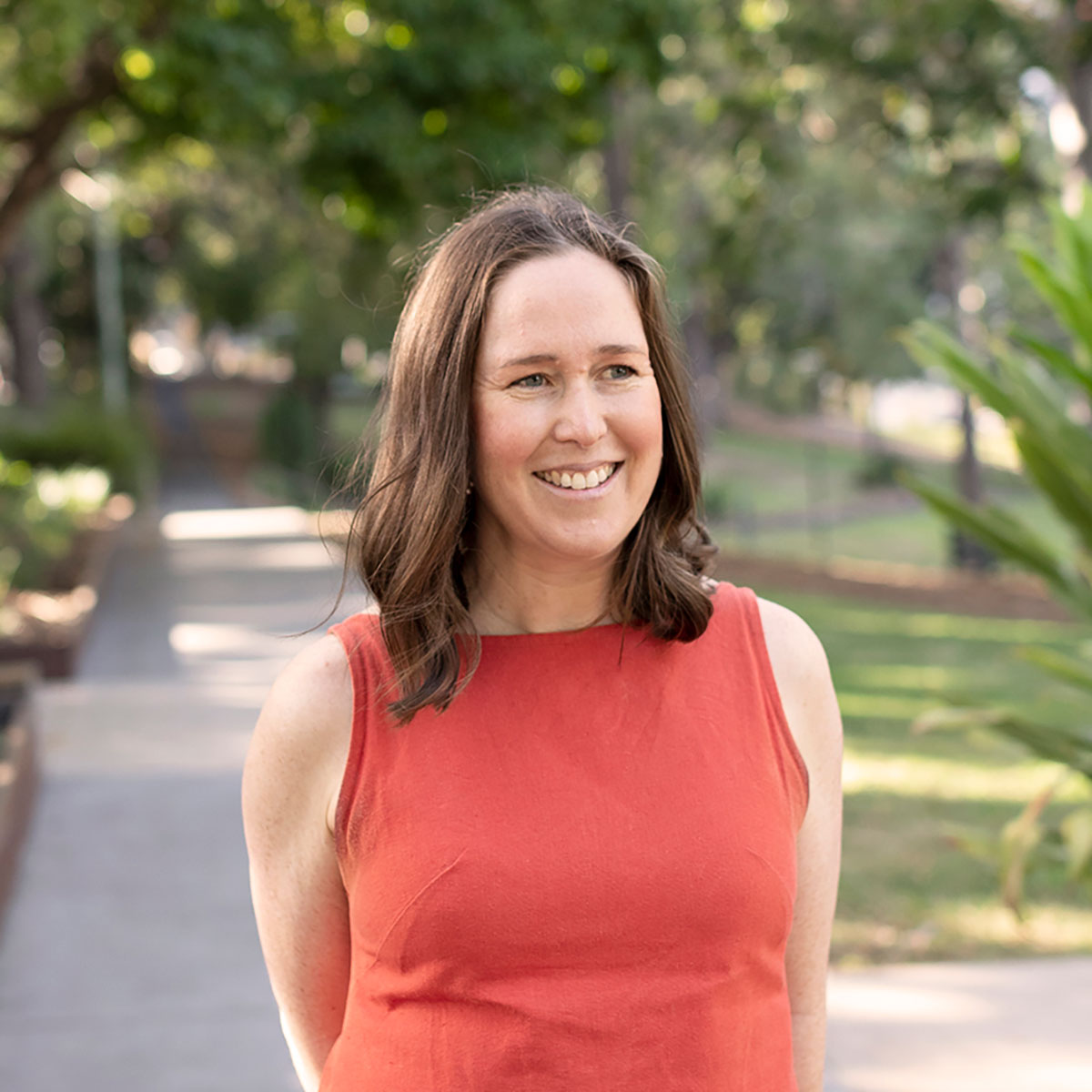 Fulton Trotter's Senior Associate, Hayley Crofts in a coral blouse, standing in Roma Street Parkland.