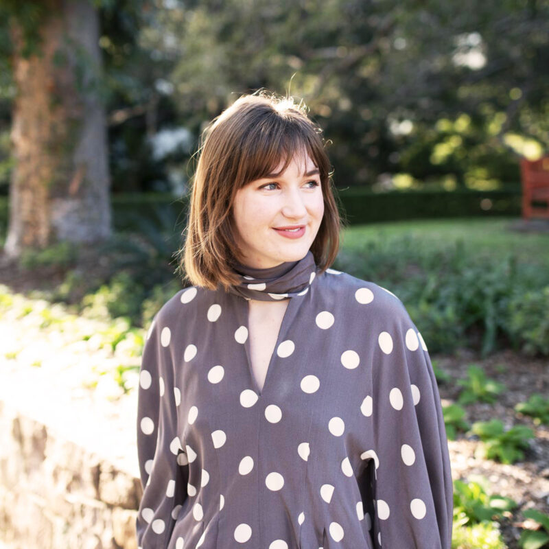 Interior Associate Erin Dawson smiling in Roma Street Parkland in navy and polka dot blouse.