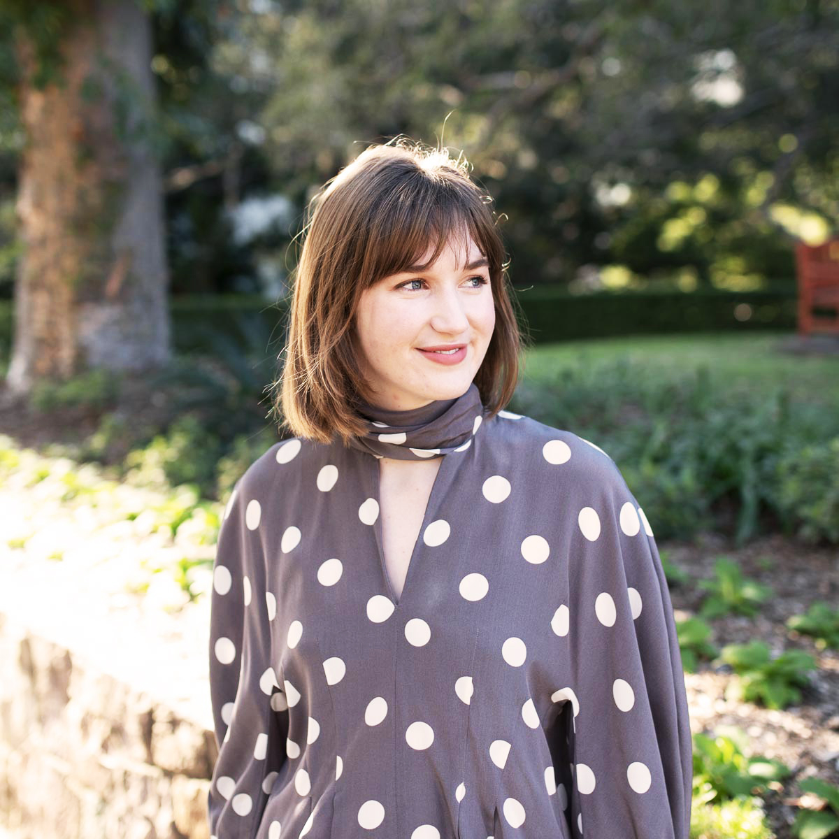 Interior Associate Erin Dawson smiling in Roma Street Parkland in navy and polka dot blouse.