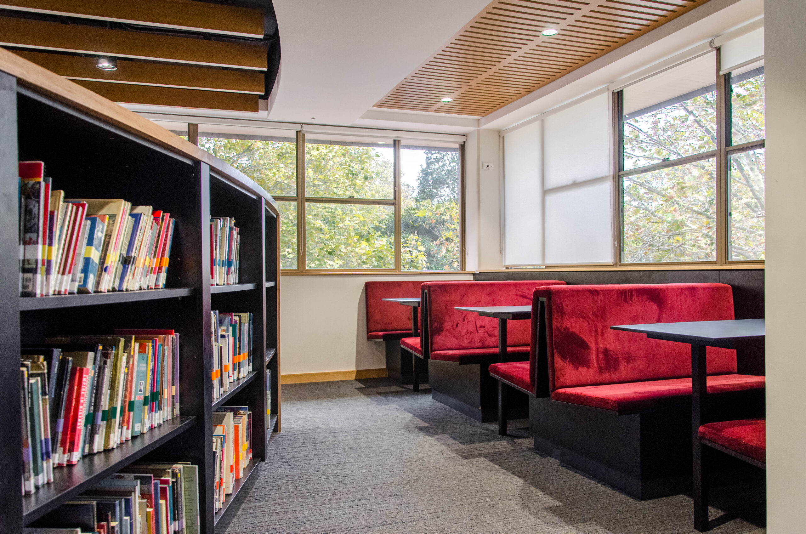 Interior of St Mary's Cathedral College in Sydney with red booth seating and a shelf with books.