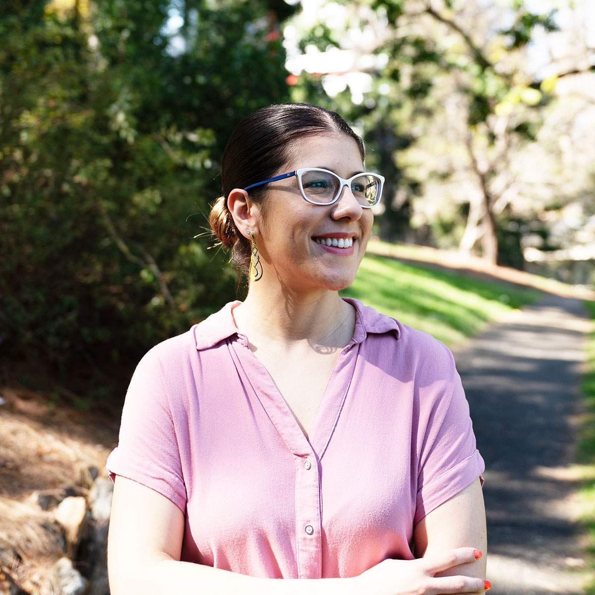 Submissions Coordinator Gabriela Chiele smiling in Roma Street Parkland in pink blouse.