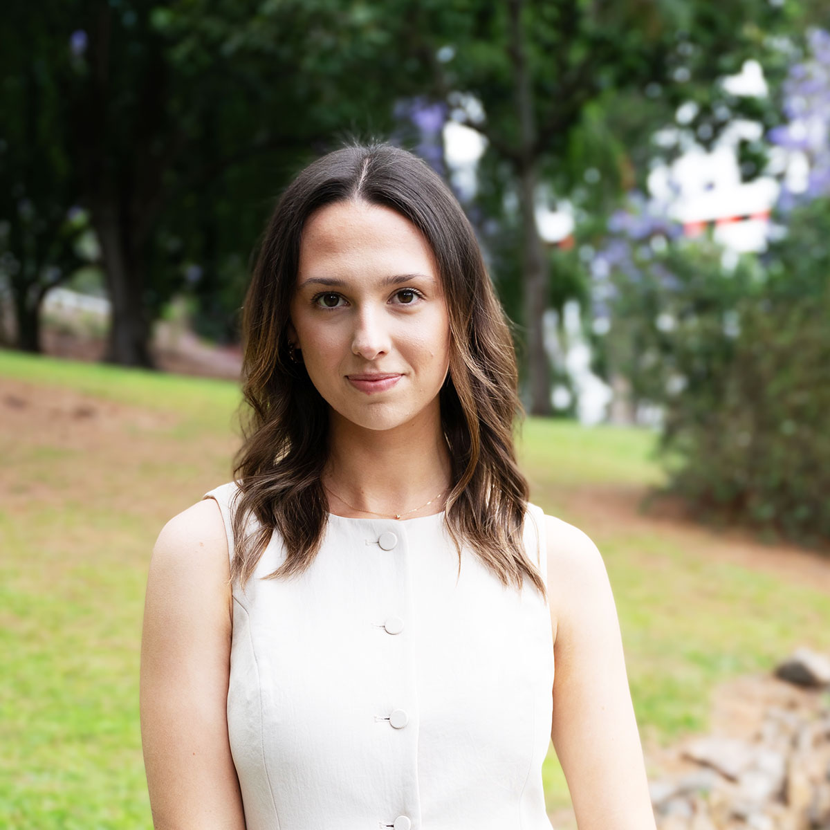 Lizzie Yarnall, Fulton Trotter Architects' Student of Architecture, standing in a green park with a white blazer-style blouse.