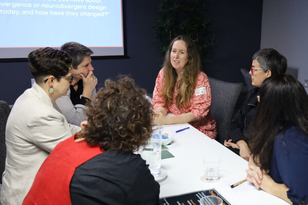 Six architects discussing how to design for neurodiversity, sitting at a white table.