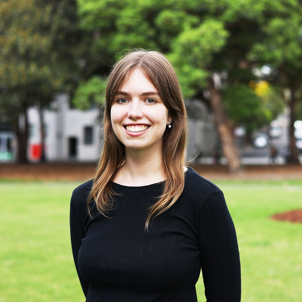 Fulton Trotter Architects' Student of Architecture, Hannah Gascon smiling in a green park and wearing a black blouse.